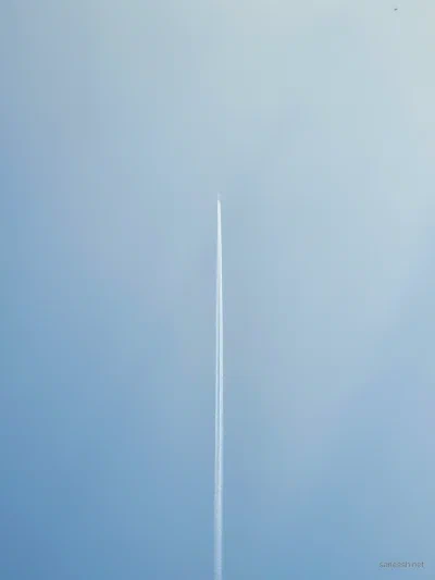 A thin white streak crossing a pale blue sky