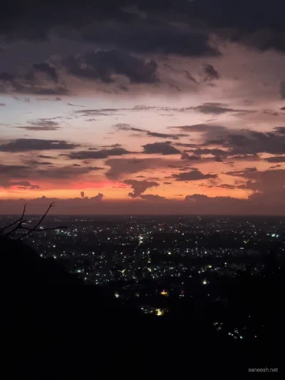 An orange and purple sunset above a distant city