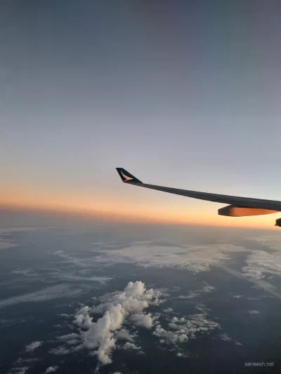 An airplane wing above clouds at sunset