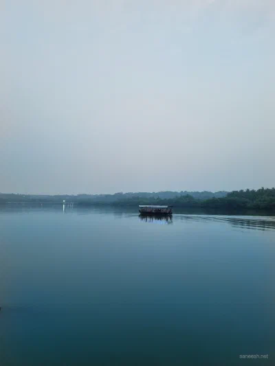 Still water and a distant shoreline beneath a hazy sky